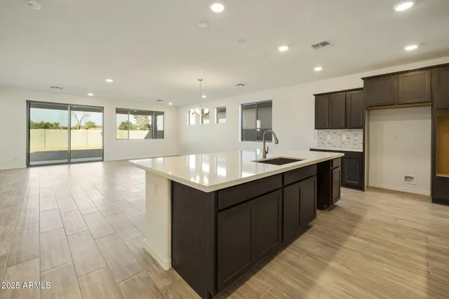 a large kitchen with stainless steel appliances a large counter top a sink a refrigerator and a cabinets