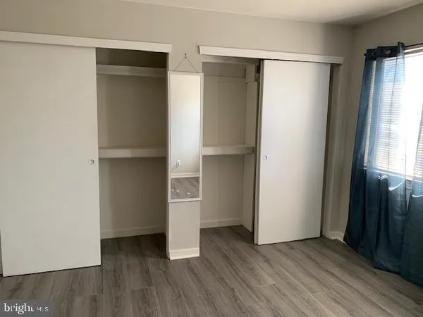 an empty room with wooden floor closet and windows