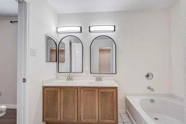 an empty room with wooden floor chandelier fan and windows