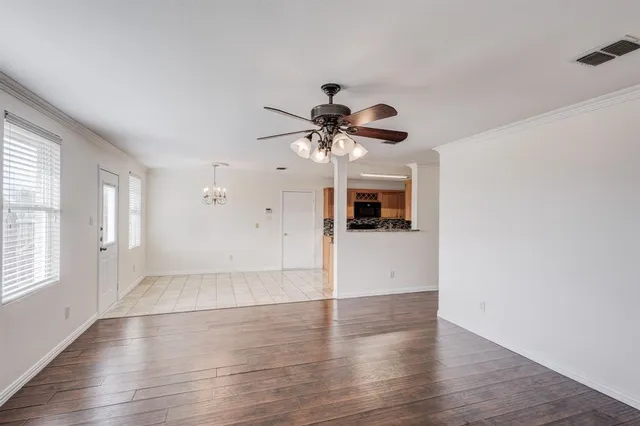 a view of an empty room with chandelier fan and fire place