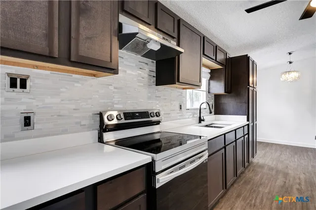 a kitchen with stainless steel appliances a stove a sink a refrigerator and wooden cabinets