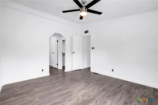 an empty room with wooden floor and a ceiling fan