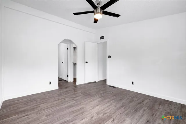 an empty room with wooden floor and a ceiling fan