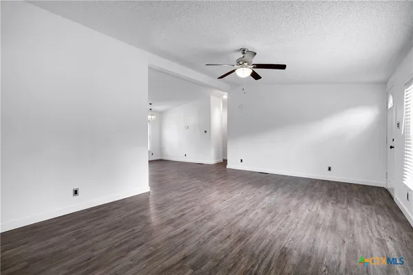 an empty room with wooden floor ceiling fan and window