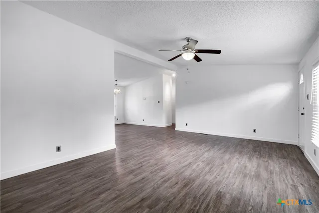 an empty room with wooden floor ceiling fan and window