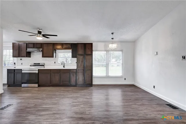 a view of kitchen with stainless steel appliances kitchen island a sink dishwasher a stove and a refrigerator with wooden floor