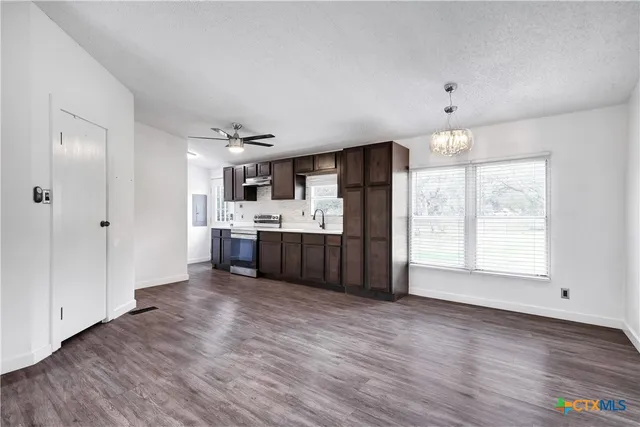 a kitchen with stainless steel appliances a sink wooden floor and a large window