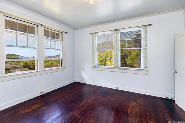a view of an empty room with a window and wooden floor