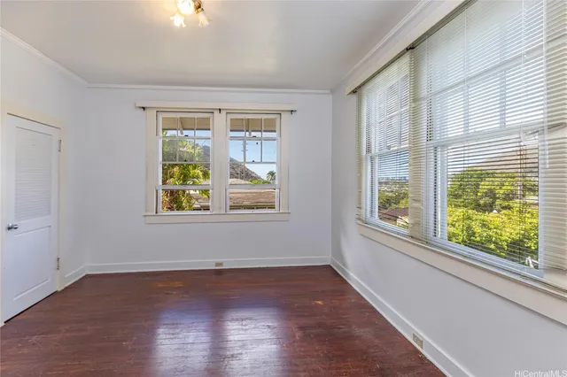 a view of an empty room with wooden floor and a window