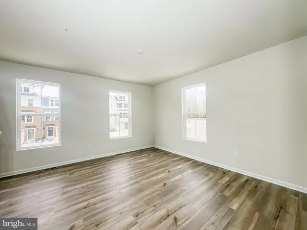 a view of an empty room with wooden floor and window
