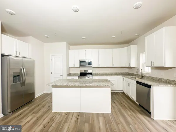 a large kitchen with stainless steel appliances granite countertop a stove a sink and a refrigerator