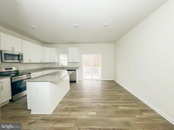 a large kitchen with cabinets wooden floor and stainless steel appliances