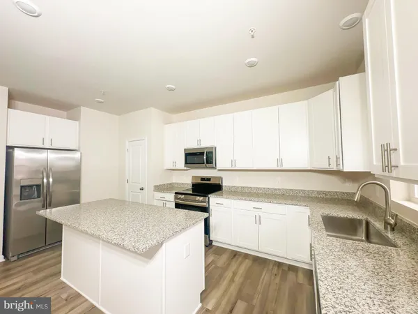 a kitchen with granite countertop a sink a counter top space stainless steel appliances and cabinets