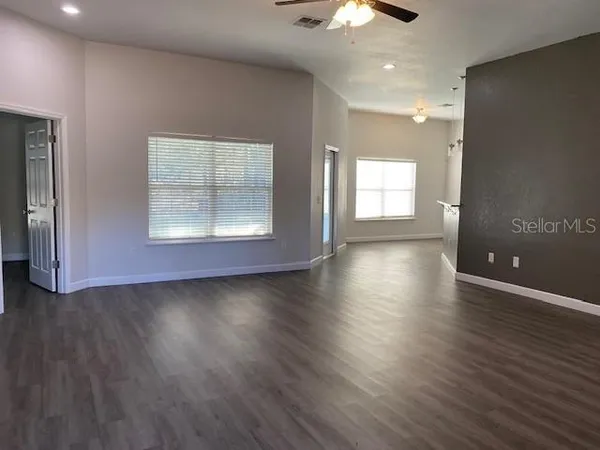 an empty room with wooden floor and windows