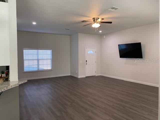 9050 Northeast 80th Street Bronson, FL 32621 - Photo 3 of 12 a view of an empty room with a flat screen tv and wooden floor