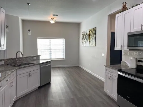 a kitchen with granite countertop a stove a sink and a microwave