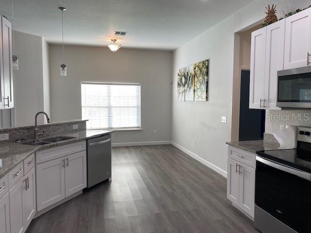 9050 Northeast 80th Street Bronson, FL 32621 - Photo 7 of 12 a kitchen with granite countertop a stove a sink and a microwave