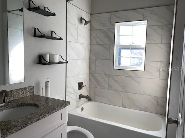 a bathroom with a granite countertop sink and a bathtub
