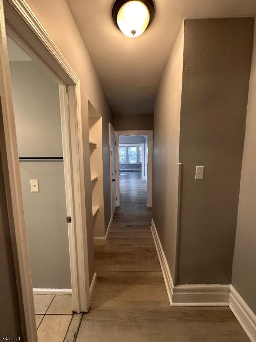 87 Lyons Avenue Newark, NJ 07112 - Photo 11 of 13 a view of a hallway with wooden floor and staircase