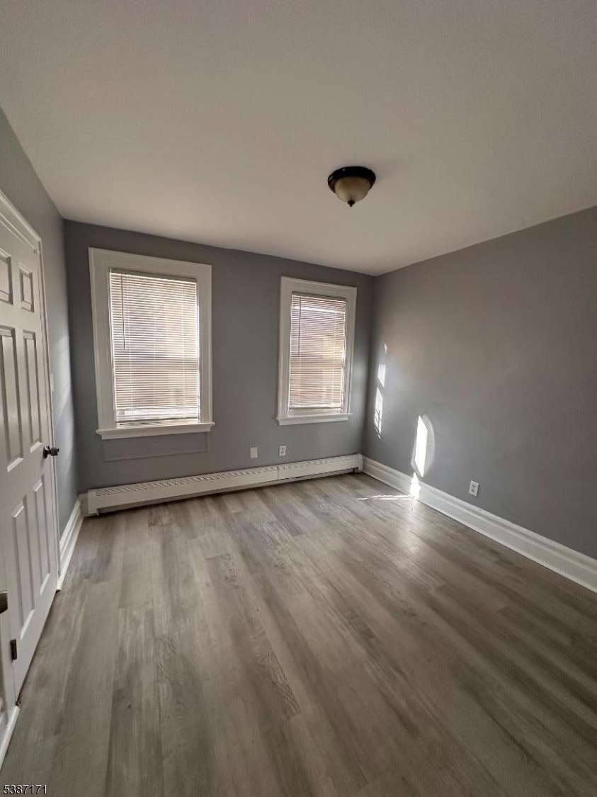 87 Lyons Avenue Newark, NJ 07112 - Photo 8 of 13 an empty room with wooden floor and windows