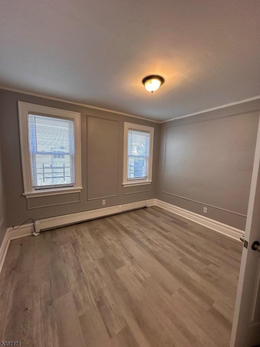 87 Lyons Avenue Newark, NJ 07112 - Photo 9 of 13 an empty room with wooden floor and windows