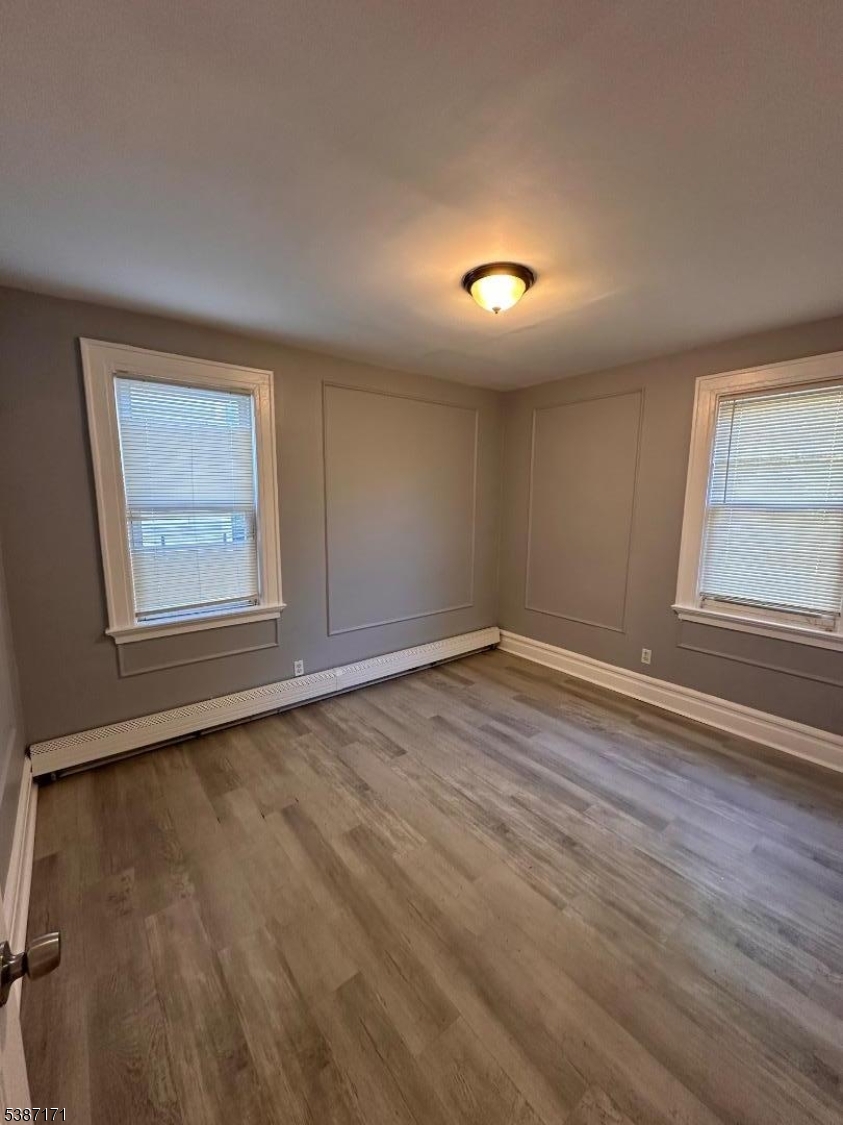 87 Lyons Avenue Newark, NJ 07112 - Photo 10 of 13 an empty room with wooden floor and windows