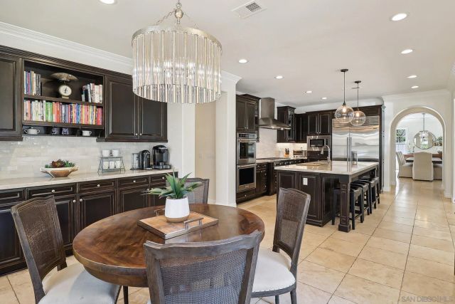 a kitchen with stainless steel appliances granite countertop a stove a refrigerator a kitchen island a dining table and chairs