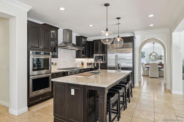 a kitchen with stainless steel appliances granite countertop a stove top oven a sink and a refrigerator