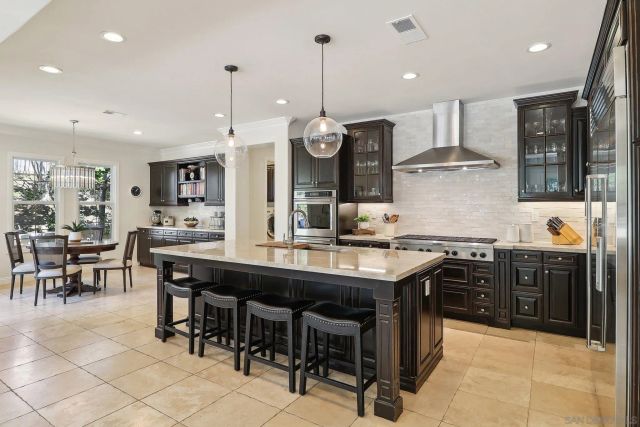 a kitchen with stainless steel appliances granite countertop a stove top oven a sink a dining table and chairs