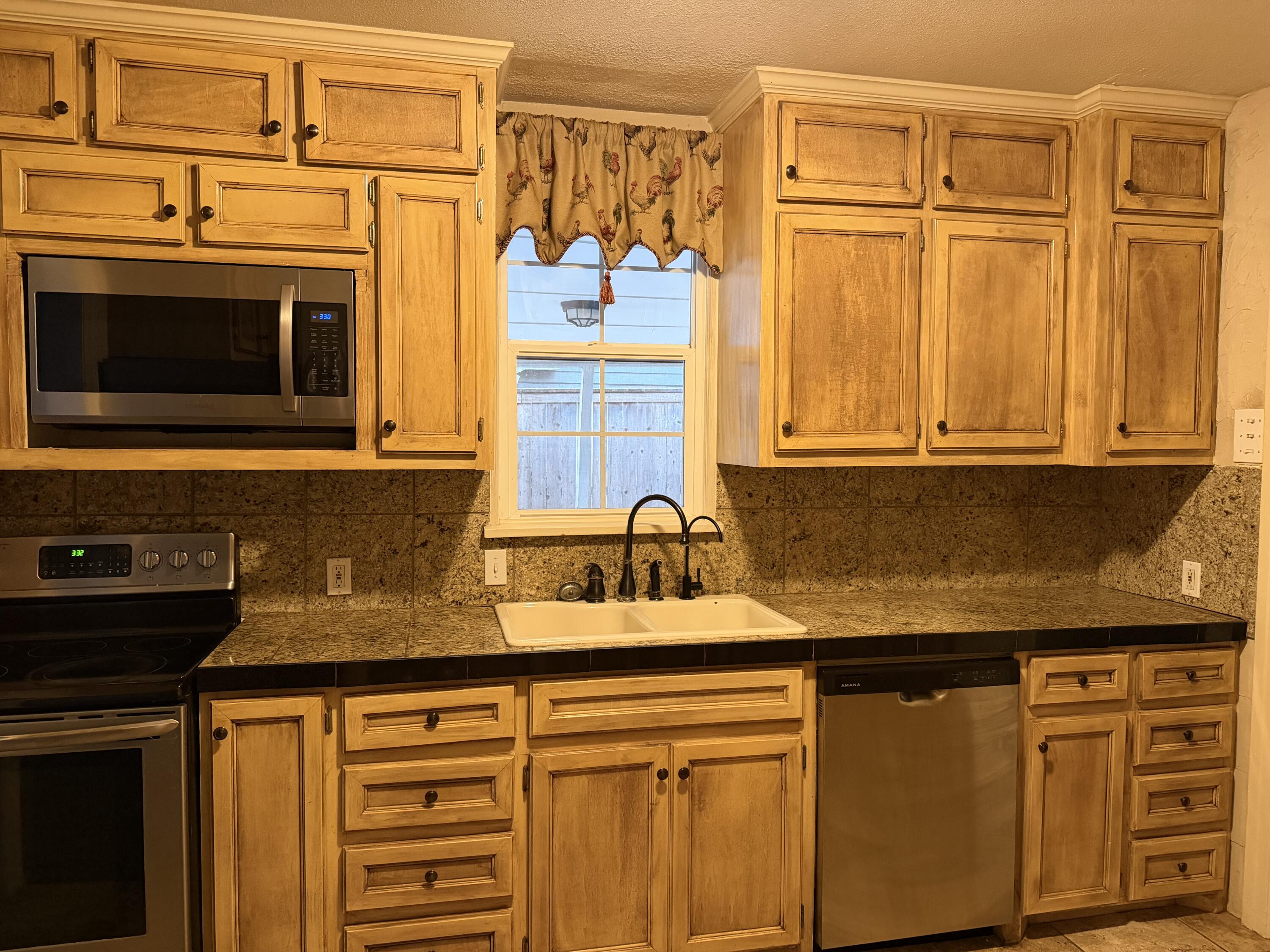 3110 22nd Street Lubbock, TX 79410 - Photo 5 of 22 a kitchen with stainless steel appliances granite countertop a sink stove and microwave