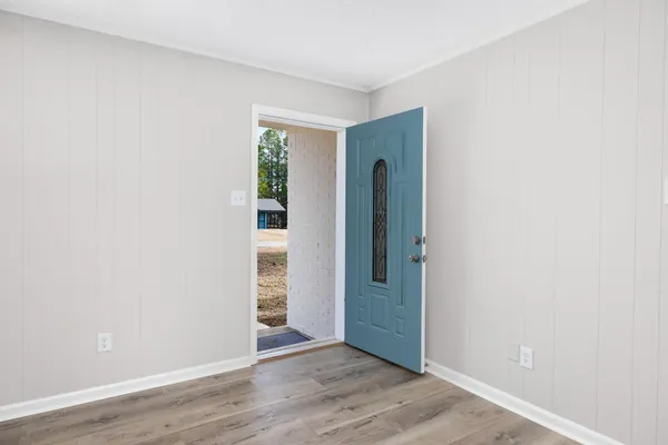 a view of an empty room with wooden floor and a window