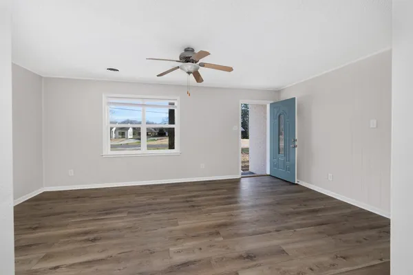 a view of empty room with wooden floor and window