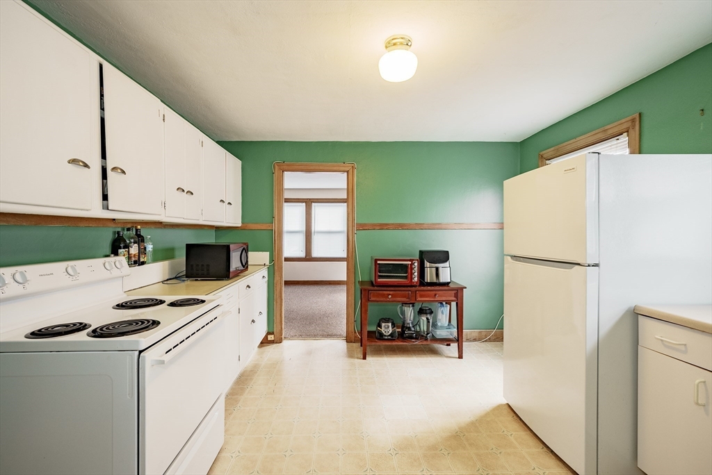 94 Holly Street Springfield, MA 01151 - Photo 23 of 41 a kitchen with a refrigerator a stove and a dining table