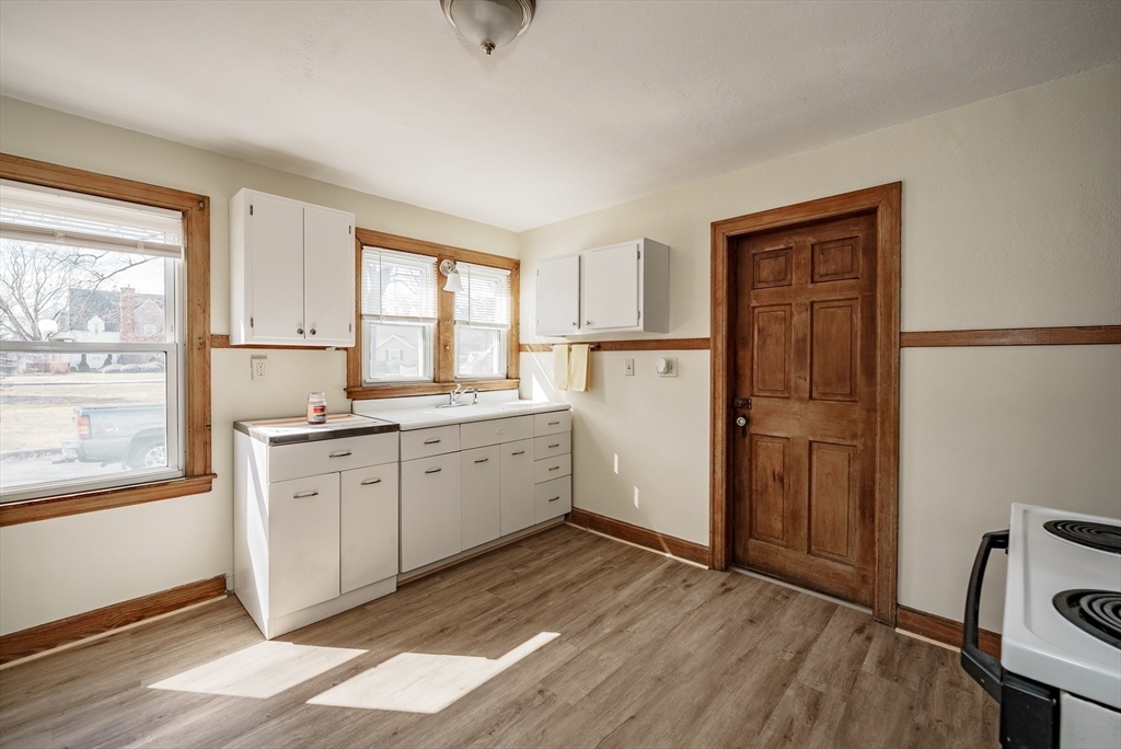 94 Holly Street Springfield, MA 01151 - Photo 8 of 41 a kitchen with white cabinets and wooden floors