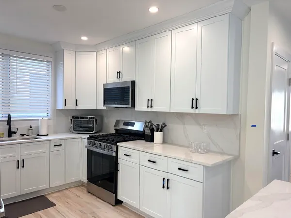 a kitchen with white cabinets appliances and a window
