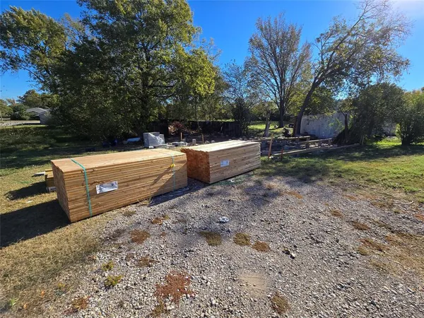 a backyard of a house with large trees and wooden fence