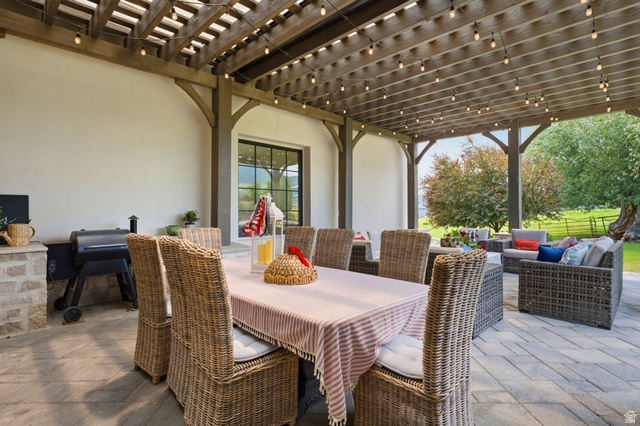 71 Farm Road Midway, UT 84049 - Photo 26 of 92 Expansive covered patio featuring a wood pergola with string lighting, stone-clad grilling station, and large format paver flooring