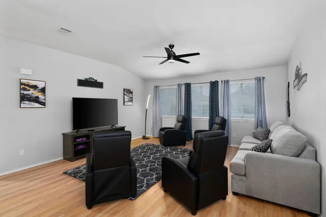 a living room with furniture a ceiling fan and a flat screen tv