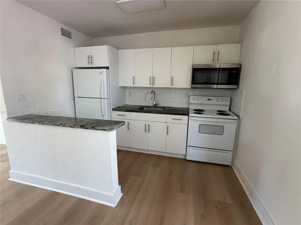a kitchen with granite countertop a sink a stove and cabinets