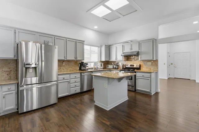 a kitchen with stainless steel appliances a sink cabinets and wooden floor