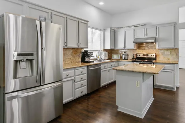 a kitchen with stainless steel appliances granite countertop a sink stove cabinets and a counter top space