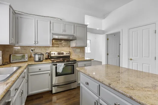 an empty room with wooden floor chandelier fan and windows