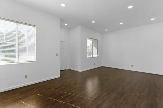 a view of an empty room with wooden floor and a window