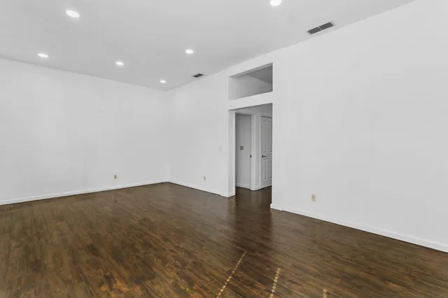 a view of an empty room with wooden floor and closet