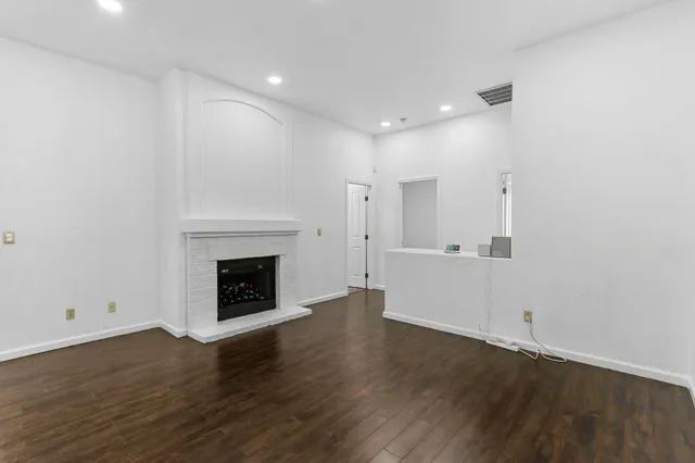 an empty room with wooden floor and a fireplace