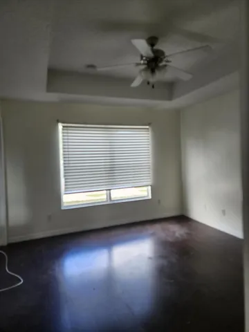 an empty room with wooden floor chandelier fan and windows