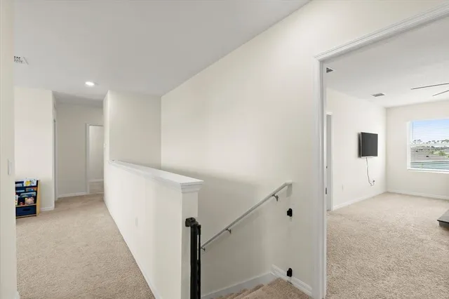a view of a hallway with stairs and a refrigerator