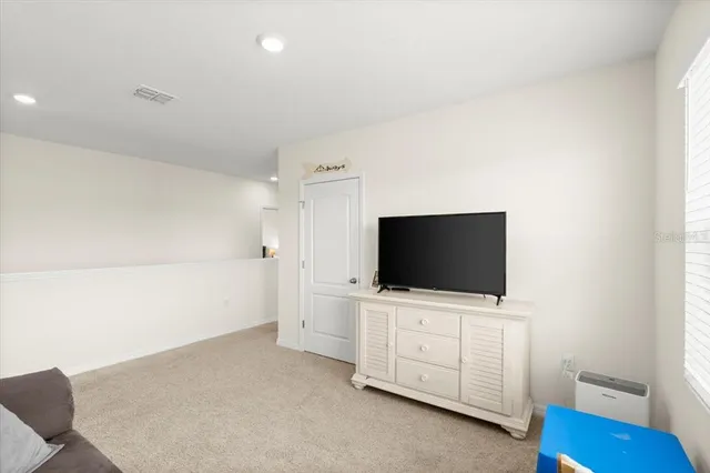 a living room with flat screen tv on the dresser and a flat screen tv