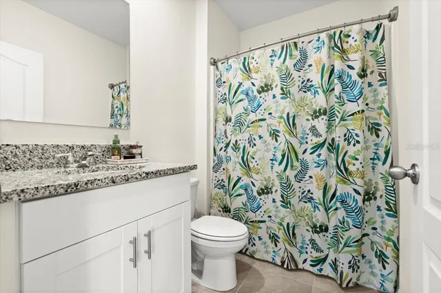 a bathroom with a granite countertop sink a toilet and a shower curtain