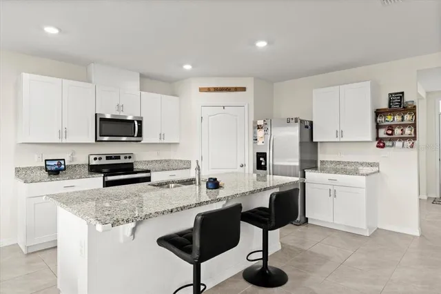 a kitchen with stainless steel appliances granite countertop a stove top oven a sink dishwasher and a refrigerator with wooden floor